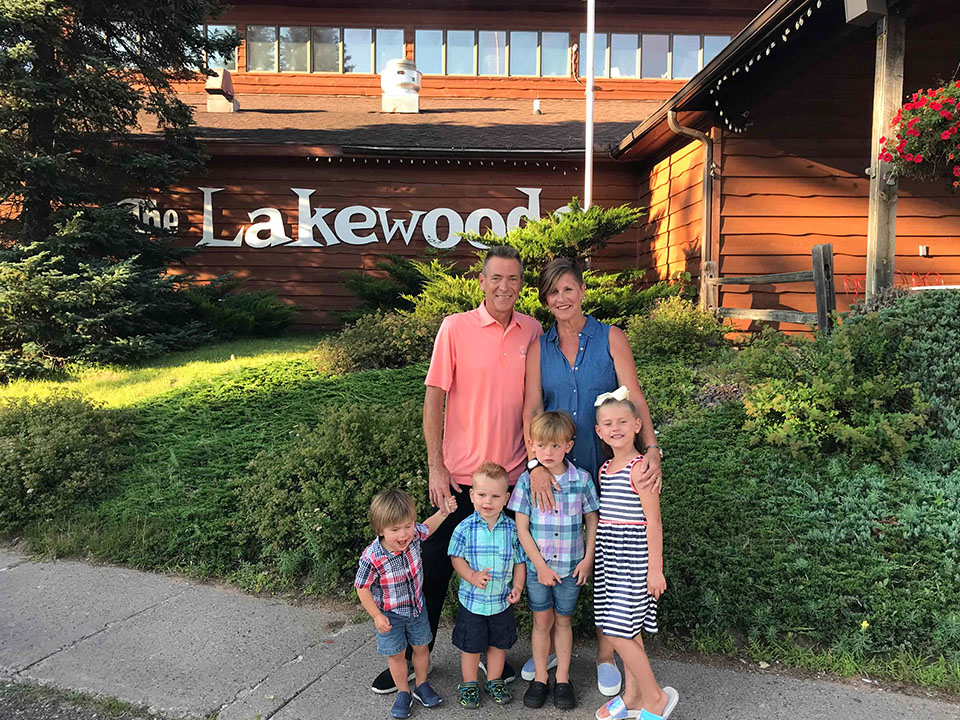 Family with four young children posing in front of the Lakewoods sign.