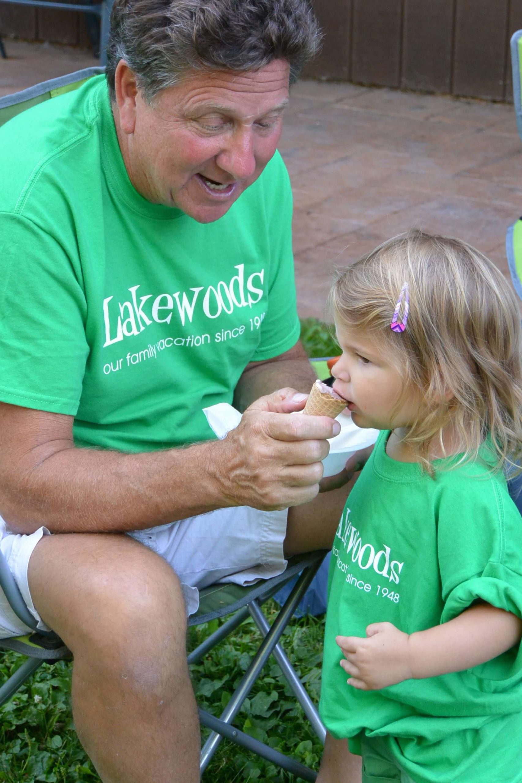 Grandparent letting a young girl try ice cream.