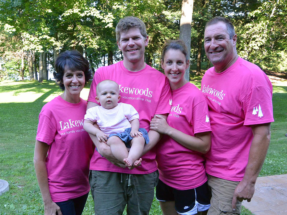 Family in pink Lakewoods shirts holding an infant