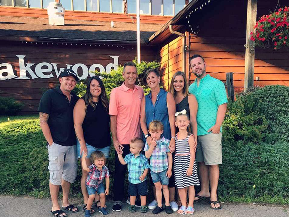 Several families posing in front of the Lakewoods sign.