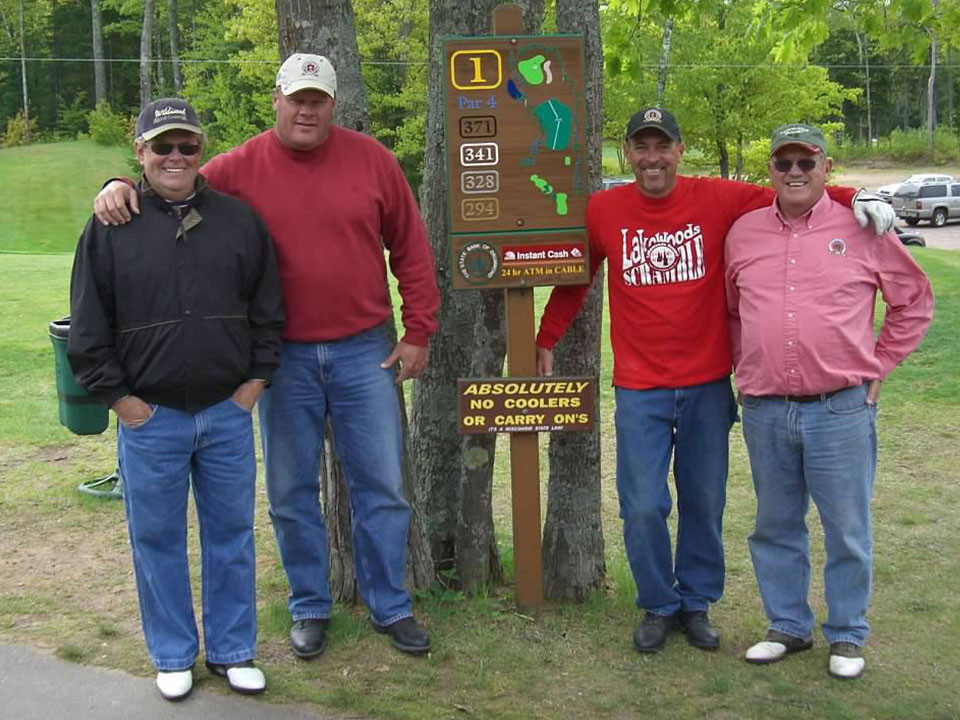 Golfers posing next to first hole sign