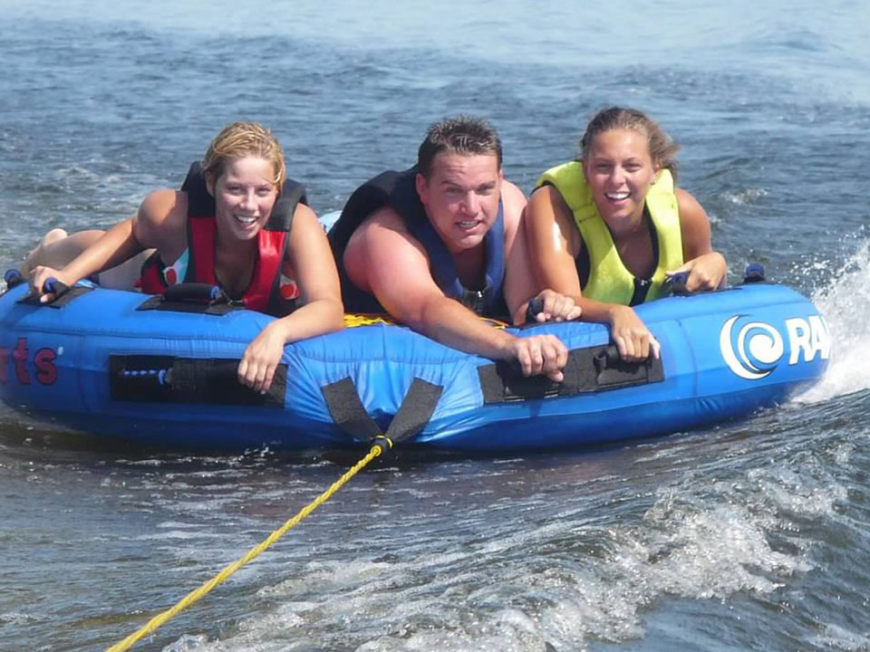 Two women and a man riding on a floating inner tube