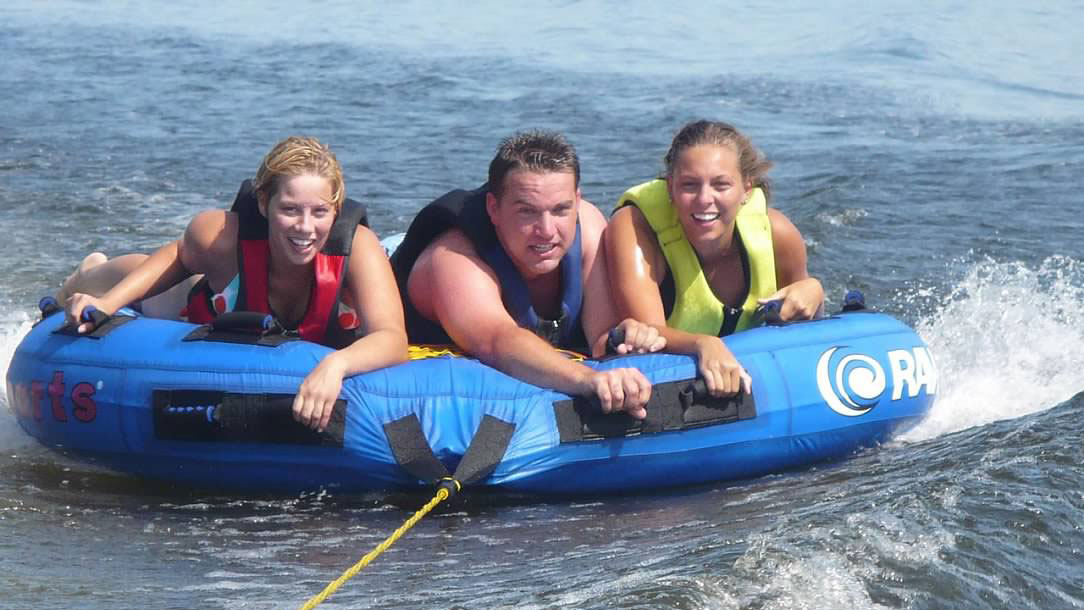 Two women and a man riding on a floating inner tube
