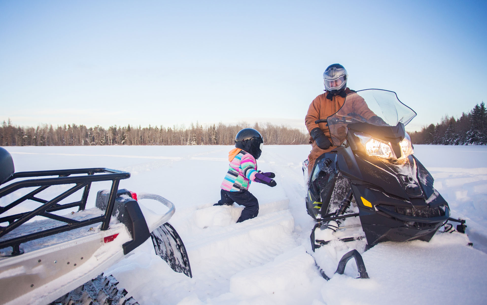 Dad and daughter on snowmobiles on ice