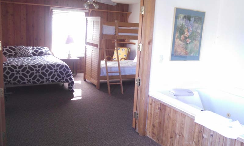 Cabin bedroom with full bed, bunk bed, jacuzzi tub