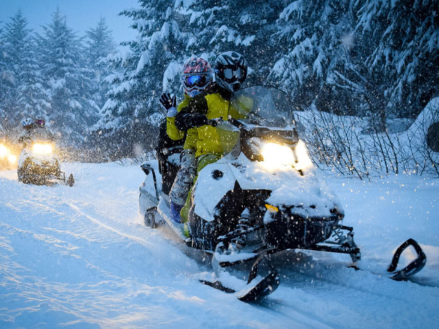 Snowmobiles on trail in snowfall