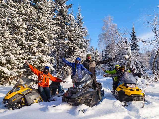 Group on snowmobiles posing for a photo