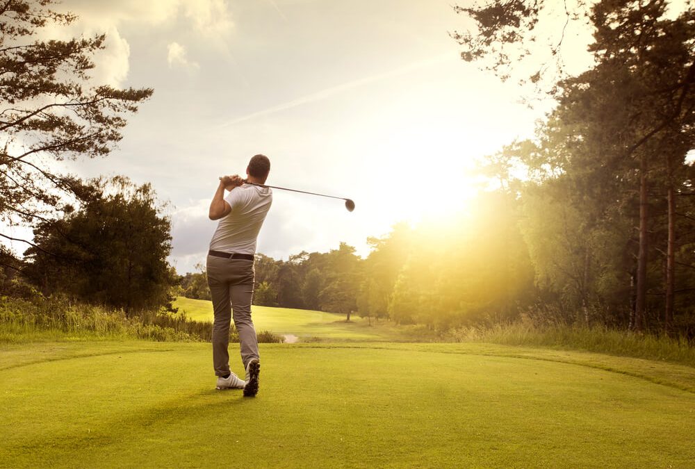 A man golfs with his back to the camera, facing the sunset on Forest Ridges Golf Course at Lakewoods Resort on Lake Namakagon.